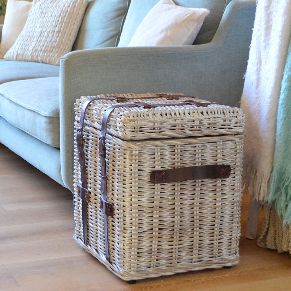 Grange rattan storage trunk positioned beside a pale blue upholstered armchair