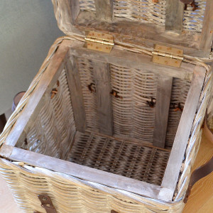 Open rattan trunk showing its woven interior, hinged lid and internal wooden frame