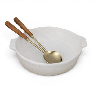Large off-white speckled ceramic baking dish with two serving spoons on a white background