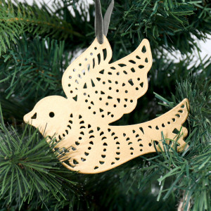 Close-up of a gold cutout dove decoration hanging from an olive green velvet loop among Christmas tree branches