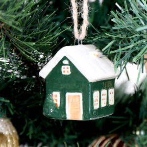 Close-up of green ceramic bungalow bauble with a snowy white roof, white window surrounds and a small tree detail