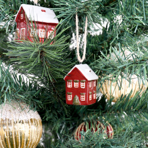 Red house bauble hanging beside a coordinating red bungalow and gold ornaments on a Christmas tree