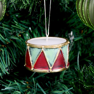 Close-up of red and soft green drum Christmas ornament with gold rope-effect detailing hanging on a tree