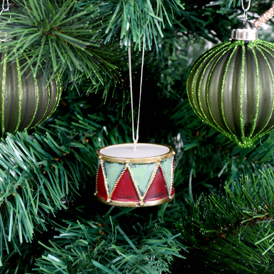 Little Drummer Christmas ornament hanging among green branches beside glitter-striped green baubles