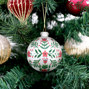 White Folklore glass bauble hanging among red and gold ornaments on a Christmas tree