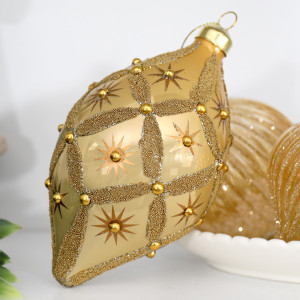 Close-up of Seraphina gold glass teardrop decoration with beaded diamond pattern, stars and raised gold accents