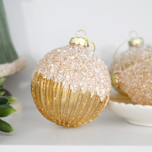 Francesca round gold bauble with glittered ribs and a sparkling top displayed beside a bowl of coordinating ornaments