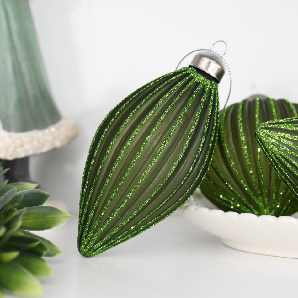Green teardrop bauble beside a white bowl of matching ornaments and foliage on a shelf