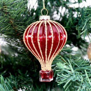Close-up of a red glass hot air balloon bauble with gold beaded stripes hanging on a Christmas tree