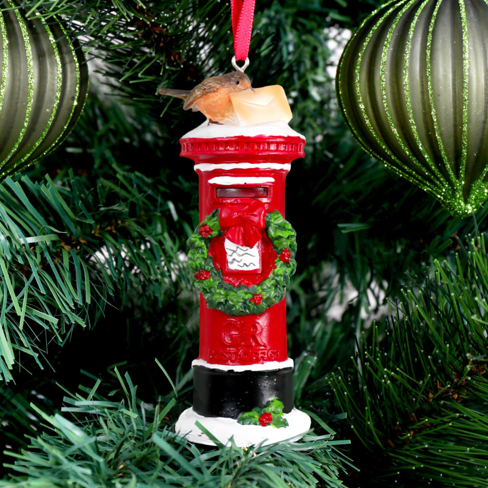 Red London mailbox ornament with a wreath, robin and envelope hanging among green Christmas tree branches