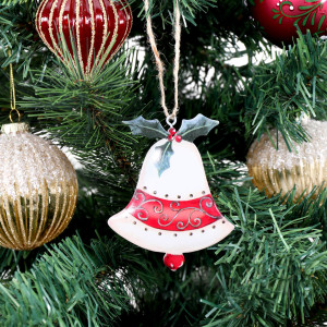 Vintage metal bell decoration hanging amongst red and gold baubles on a green Christmas tree