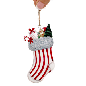 Close-up of a striped metal stocking ornament with printed presents, candy cane and gingerbread figure on a Christmas tree