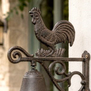Close-up of the detailed rooster and curled cast iron wall bracket