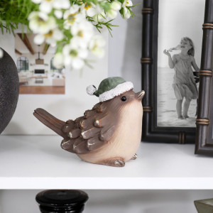 Mistletoe hat bird on a white shelf beside a dark photo frame and white flowers