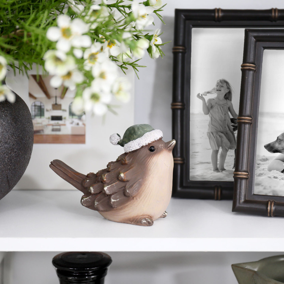 Mistletoe Bird Christmas decoration displayed with family photo frames and flowers on a white shelf