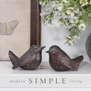 Pair of vintage brown wren figurines styled on a white book with flowers and framed butterfly art