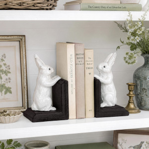 Set of two white bunny bookends with dark brown bases styled on a country bookshelf with books and decor