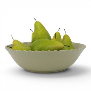 Maeve soft green scalloped serving bowl filled with green pears against a white background