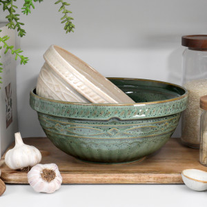 Vintage green and cream ceramic mixing bowls nested on a wooden chopping board