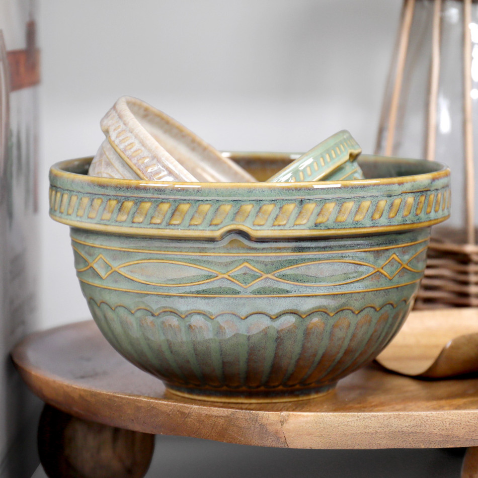 Green and cream ceramic mixing bowls nested on a wooden riser