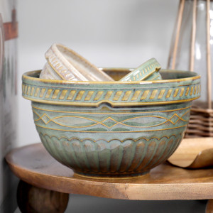 Green and cream ceramic mixing bowls nested on a wooden riser