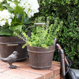 Compact rustic wooden bucket presented with an artificial plant