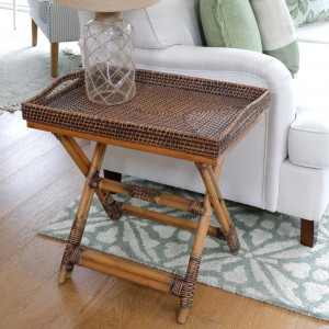 Brown woven tray table viewed from the side beside a sofa