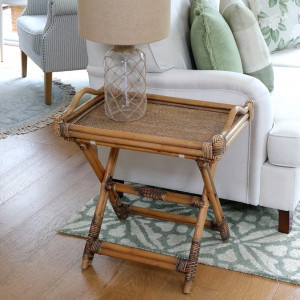 Brown butler's tray side table styled with a glass lamp beside a cream sofa