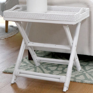 White rattan butler's tray table beside a neutral upholstered sofa