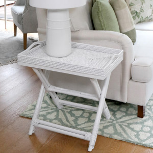 White butler's tray table beside an armchair on a patterned rug