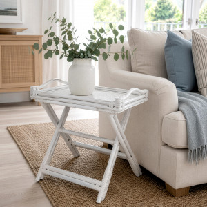White folding rattan tray table styled with a vase beside a cream sofa