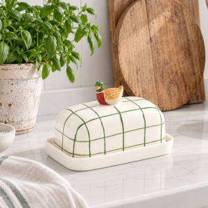 Green and white checked duck butter dish styled beside herbs and wooden boards