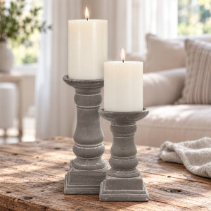 Tall and small Elstead grey cement candle holders with ivory pillar candles on a rustic wood table