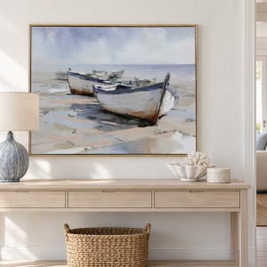 Framed rowboat canvas above a pale timber console with a blue lamp, shell bowl and woven basket