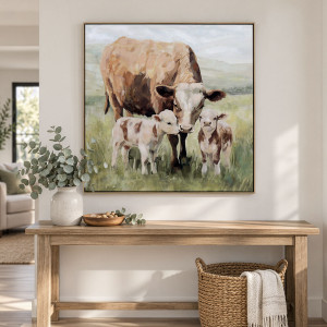 Square cow family canvas above a timber console with eucalyptus, a wooden bowl and a woven basket