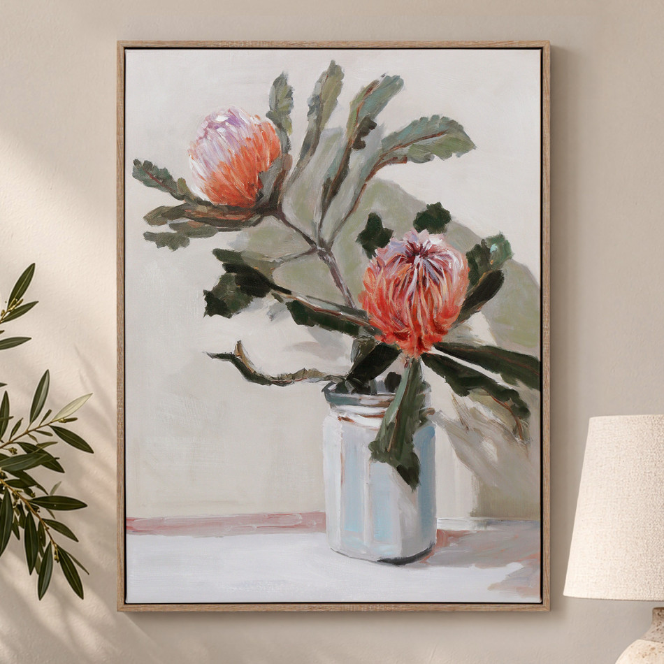 Framed banksia canvas with red-orange flowers and green foliage in a pale jar, styled beside a lamp
