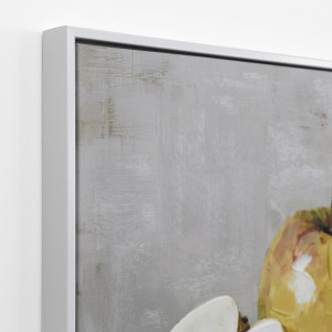 Angled close-up of the white frame and textured grey canvas surface with part of the golden apple
