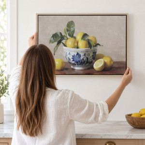 Framed lemon still life being positioned above a kitchen bench with a bowl of lemons nearby