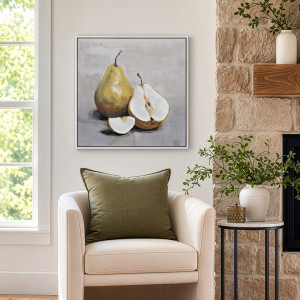 Framed pear canvas above a cream armchair with an olive cushion, beside a window and stone fireplace