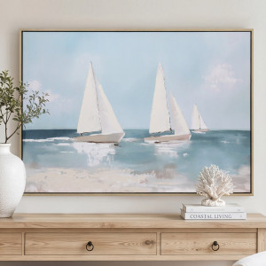 Framed blue-and-white yacht canvas above a timber console, styled with a white vase and coral ornament