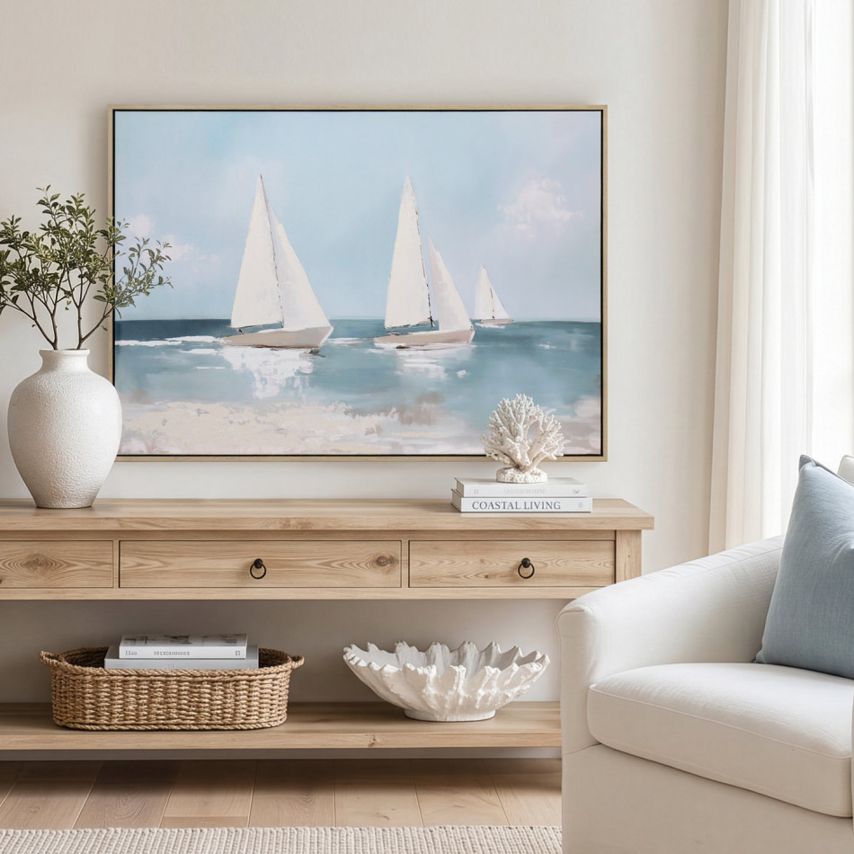 Framed yacht canvas above a coastal console with a white vase, coral ornament and woven basket beside an armchair