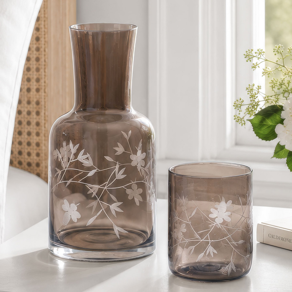 Chestnut-brown etched-glass carafe and matching botanical tumbler on a sunlit bedside table