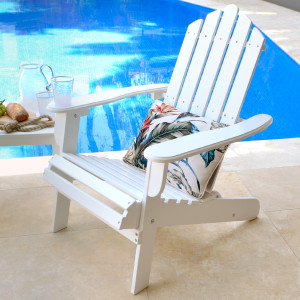 White Adirondack chair with tropical cushion positioned beside a blue swimming pool