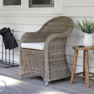 Ashford woven rattan armchair beside a round wood table on a covered verandah