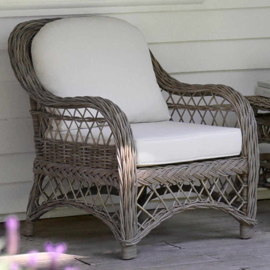 Grey-brown rattan armchair with cream cushions on a covered verandah