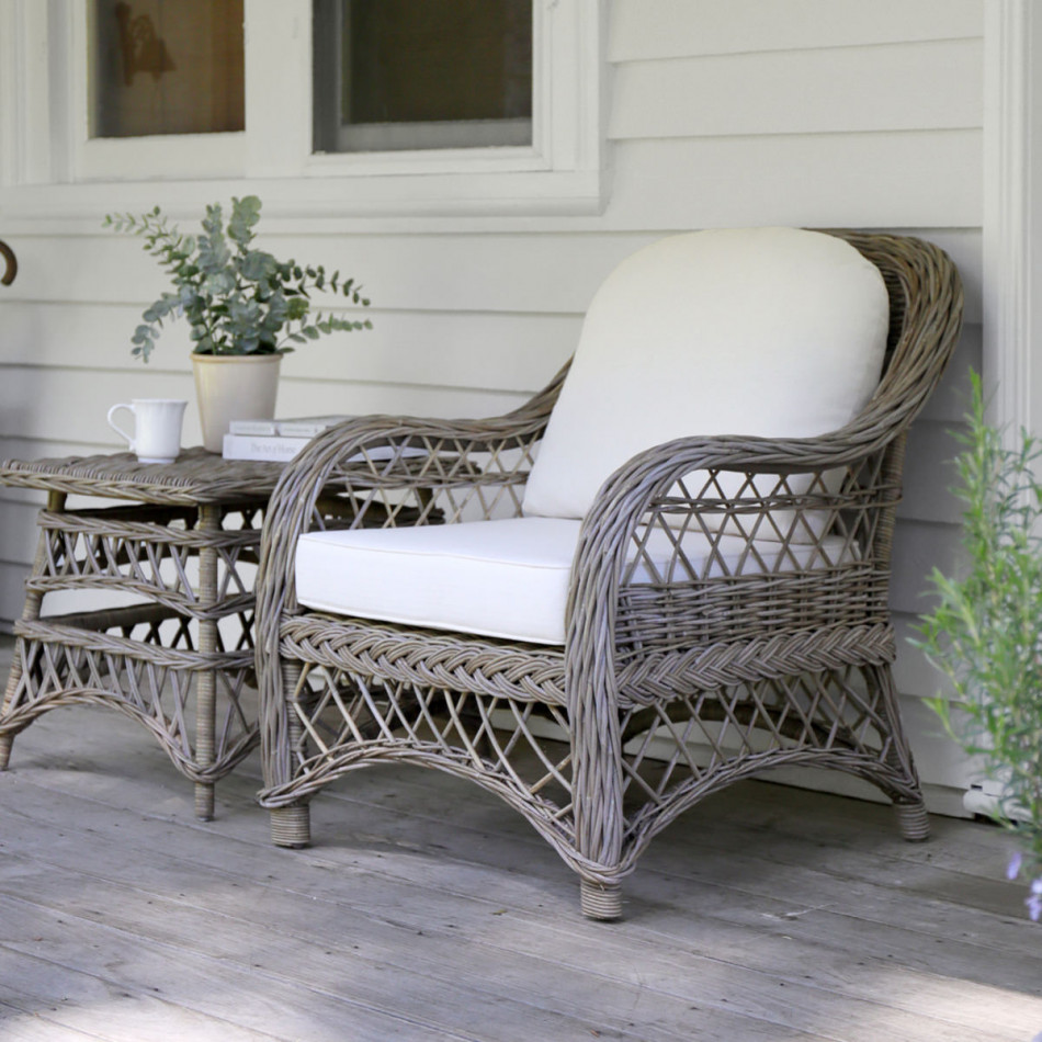 Camden rattan armchair beside a matching side table with a vase of greenery