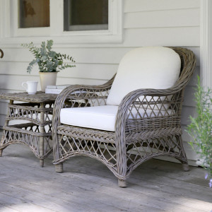 Camden rattan armchair beside a matching side table with a vase of greenery