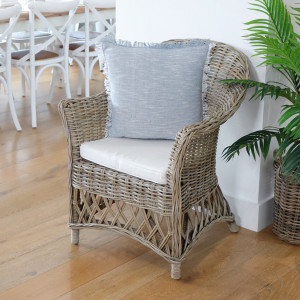 Charlotte rattan armchair with cream seat cushion and blue decorative cushion in a dining area