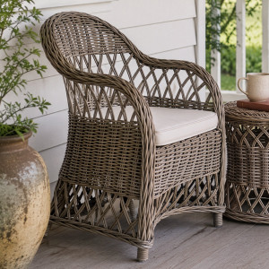 Clifton grey-brown rattan chair with cream seat cushion styled on a covered verandah