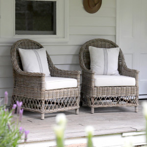 Two grey-brown rattan armchairs with cream cushions viewed from the verandah